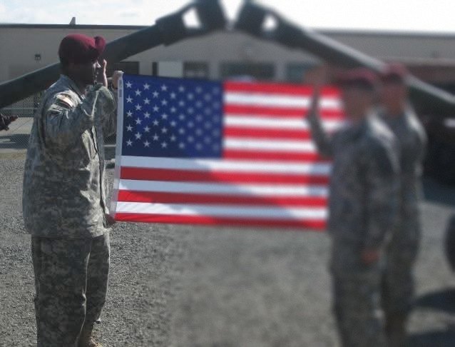 William administering the oath to soldiers in front of the flag.